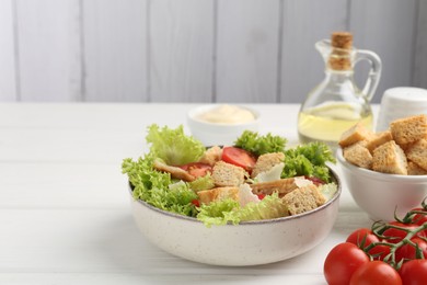 Photo of Delicious salad with croutons and ingredients on white wooden table, closeup. Space for text