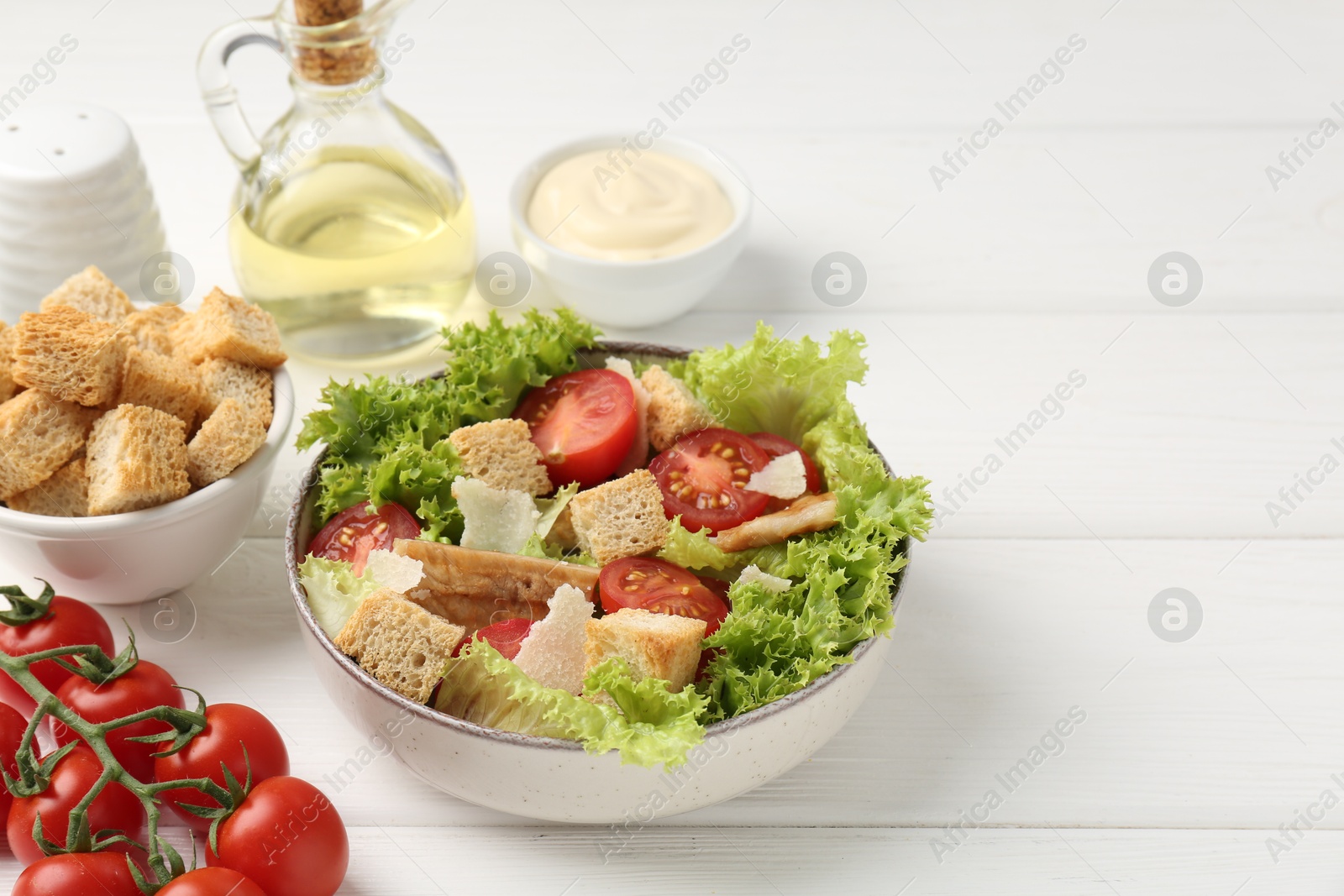 Photo of Delicious salad with croutons and ingredients on white wooden table, closeup. Space for text