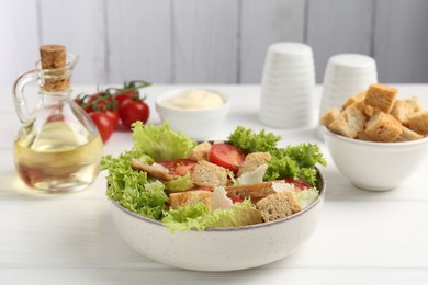 Photo of Delicious salad with croutons and ingredients on white wooden table, closeup