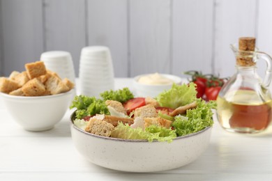 Photo of Delicious salad with croutons and ingredients on white wooden table, closeup