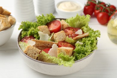 Photo of Delicious salad with croutons and ingredients on white wooden table, closeup