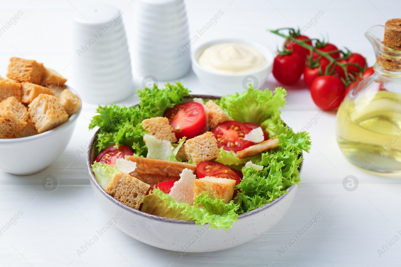 Photo of Delicious salad with croutons and ingredients on white wooden table, closeup