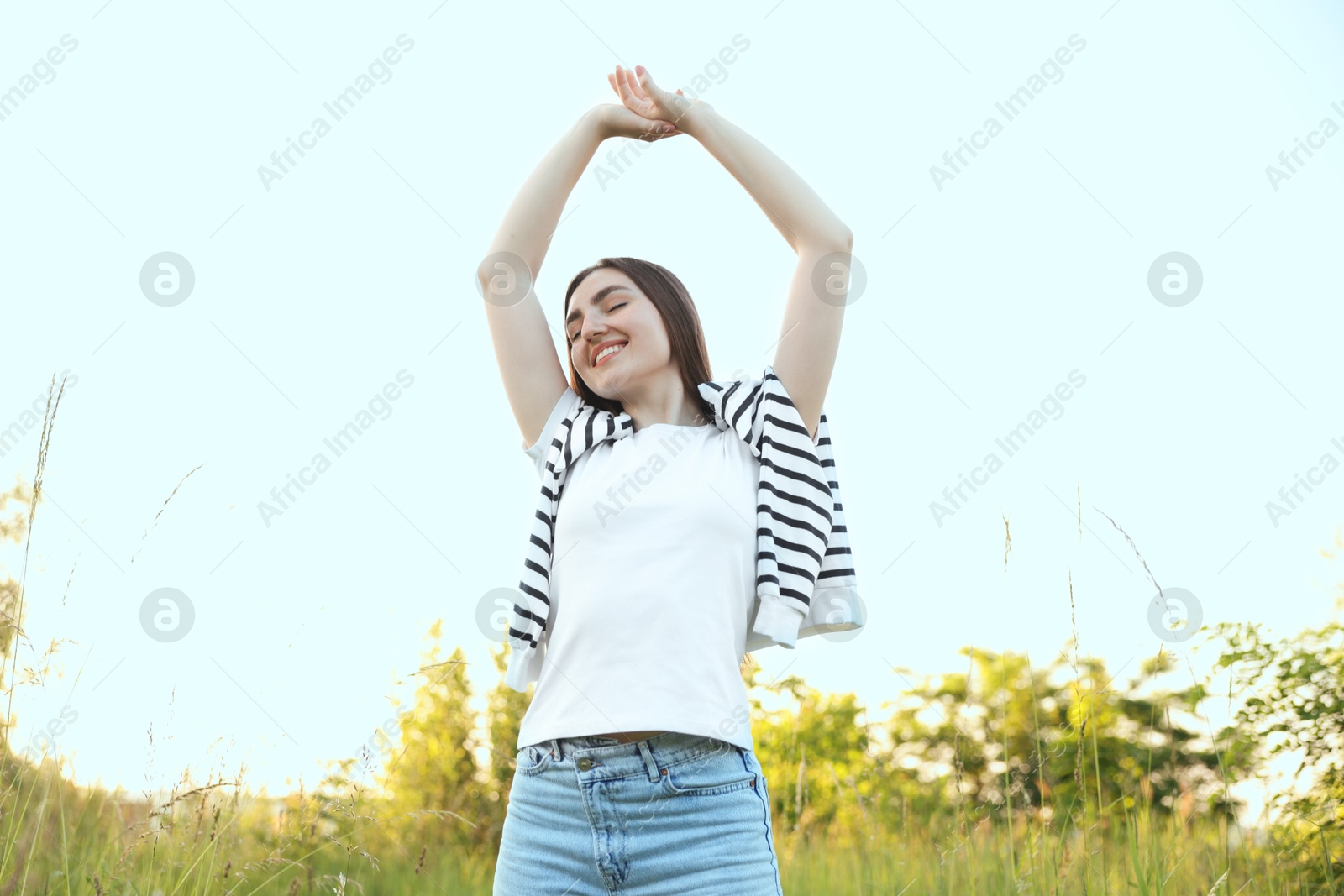 Photo of Feeling freedom. Happy young woman enjoying time in nature, low angle view