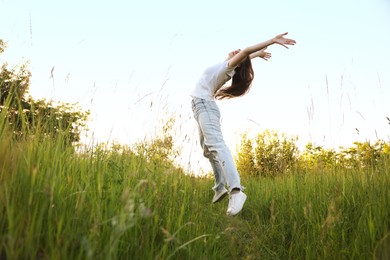 Photo of Feeling freedom. Young woman jumping in nature