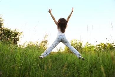 Photo of Feeling freedom. Woman jumping in nature, back view