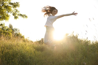 Photo of Feeling freedom. Happy young woman jumping in nature