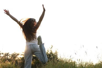 Photo of Feeling freedom. Woman jumping in nature, back view. Space for text