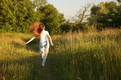 Photo of Feeling freedom. Woman running in nature, back view