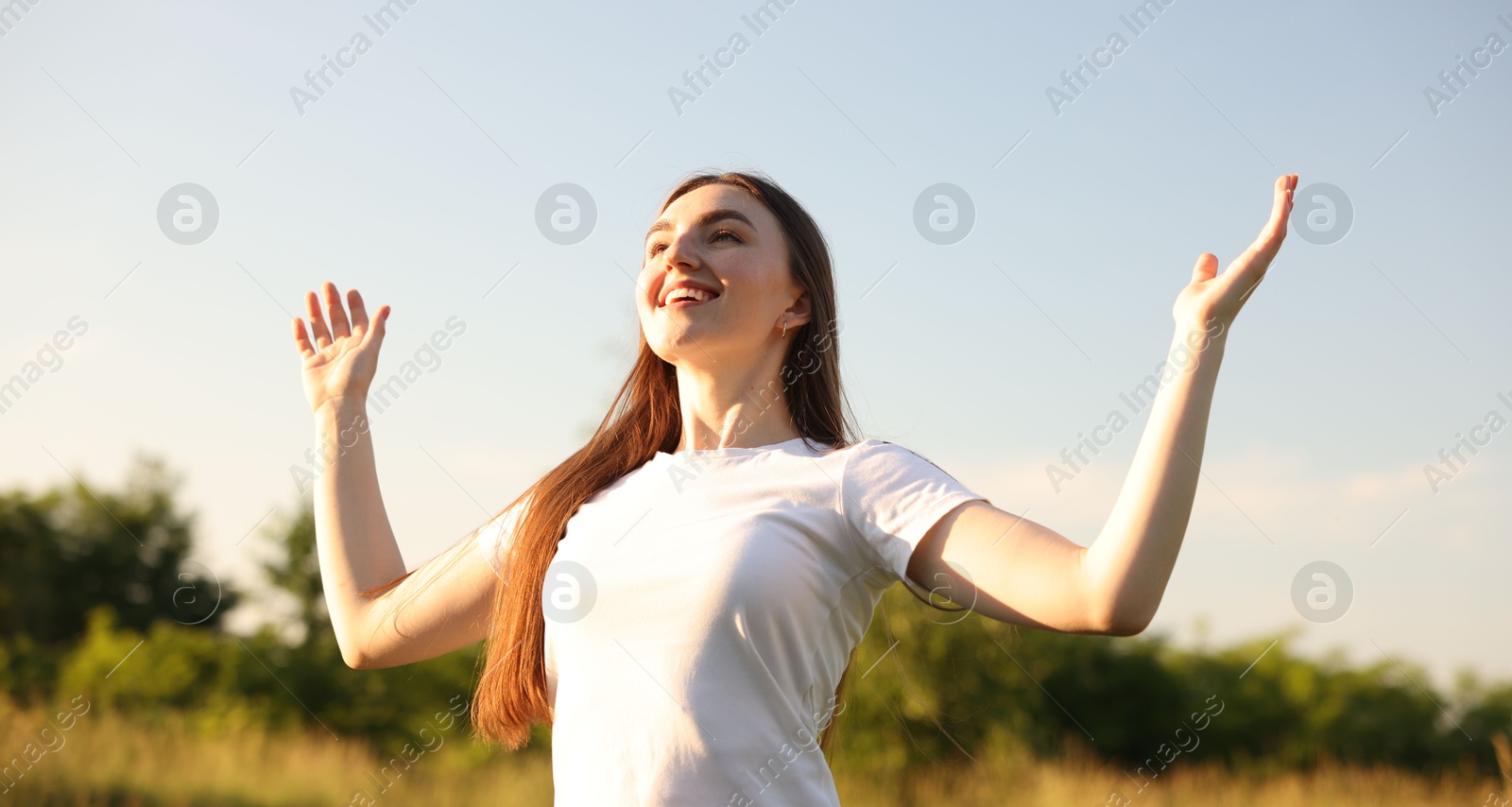 Photo of Feeling freedom. Happy young woman enjoying time in nature, low angle view