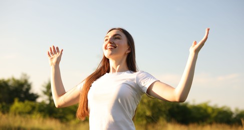 Photo of Feeling freedom. Happy young woman enjoying time in nature, low angle view