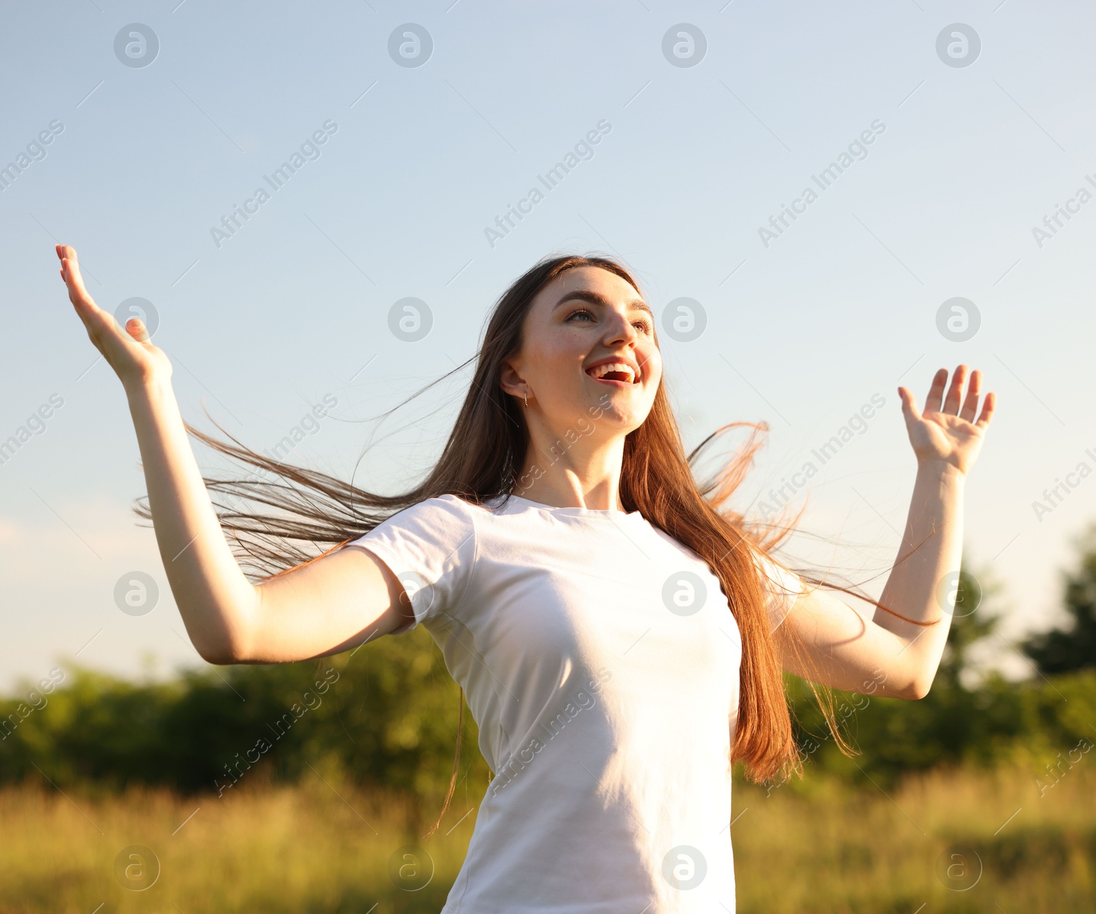 Photo of Feeling freedom. Happy young woman enjoying time in nature, low angle view