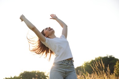 Photo of Feeling freedom. Happy young woman enjoying time in nature, low angle view