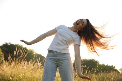 Photo of Feeling freedom. Happy young woman enjoying time in nature, low angle view