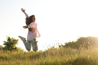 Photo of Feeling freedom. Happy young woman jumping in nature, space for text