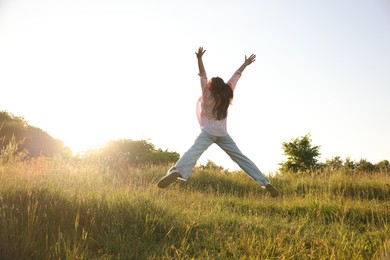 Photo of Feeling freedom. Woman jumping in nature, back view