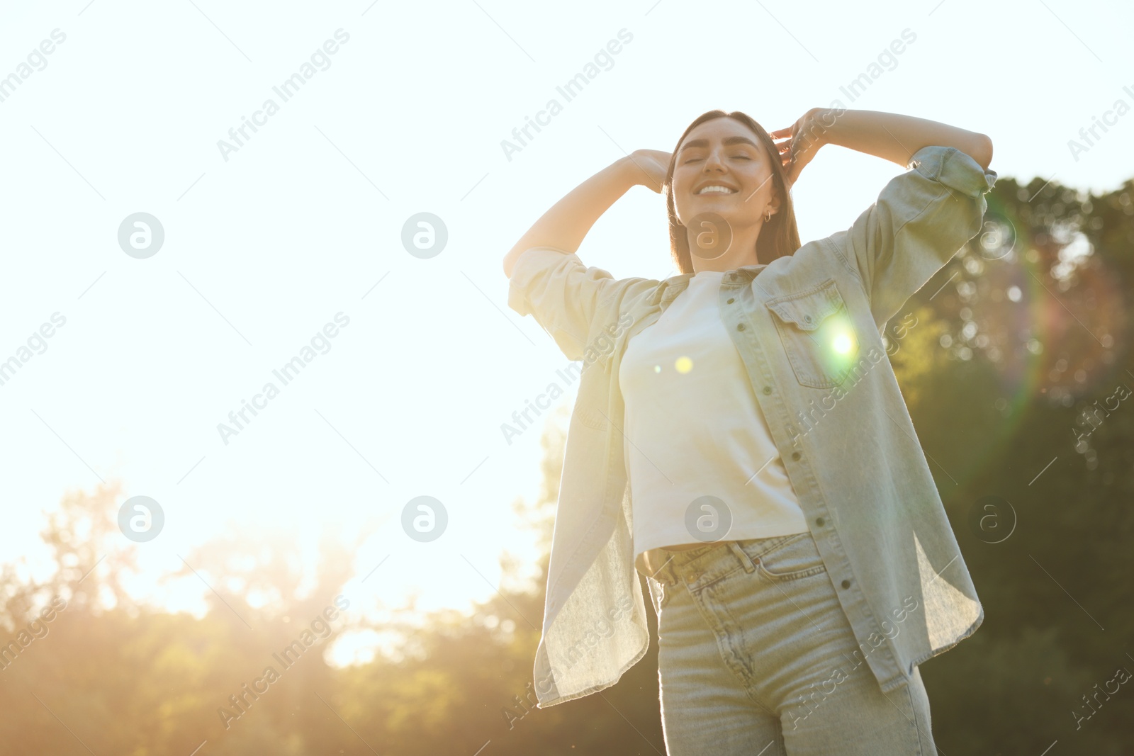 Photo of Feeling freedom. Happy young woman enjoying time in nature on sunny day, low angle view