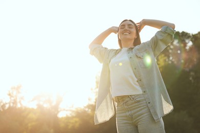Photo of Feeling freedom. Happy young woman enjoying time in nature on sunny day, low angle view