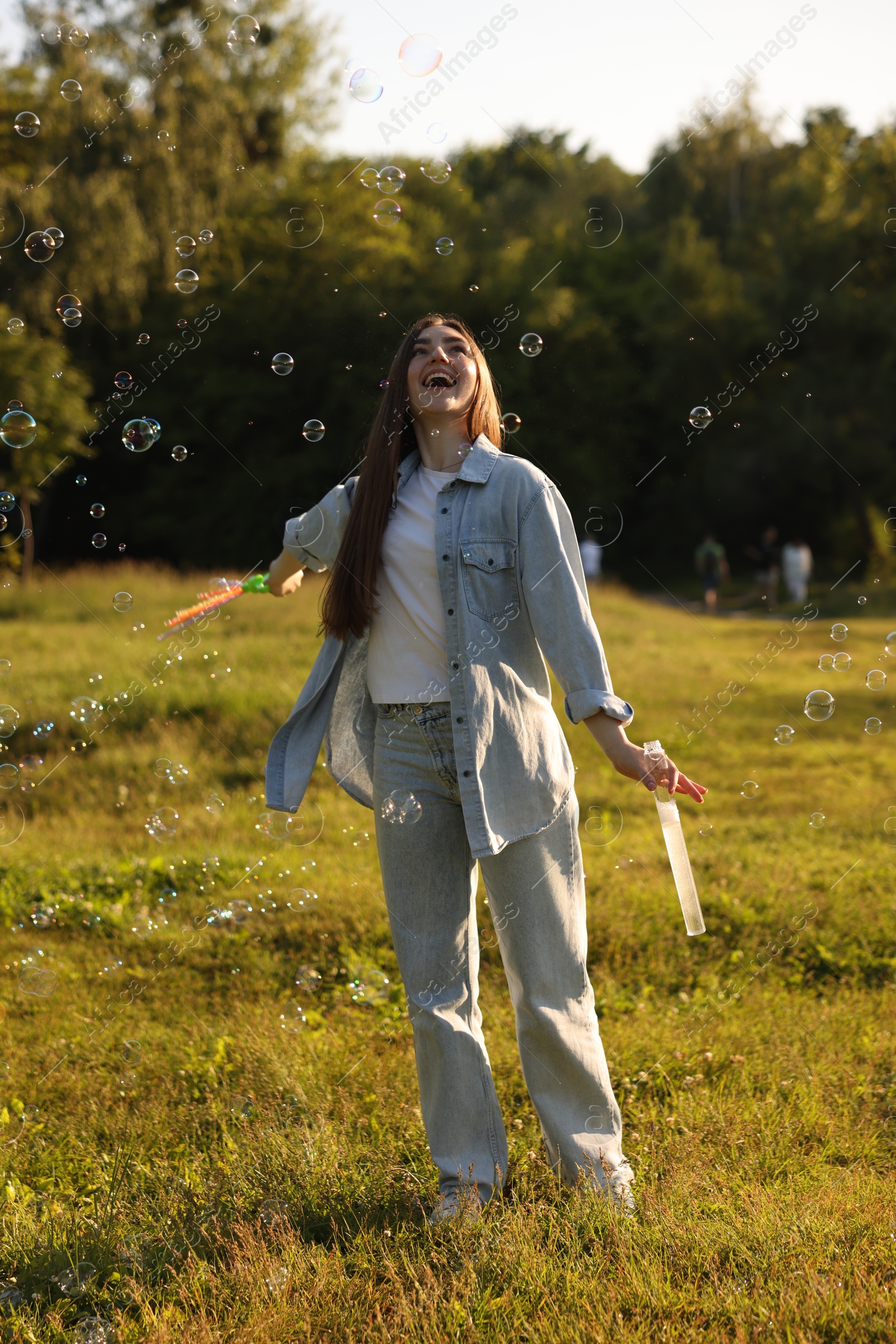 Photo of Feeling freedom. Happy young woman having fun among soap bubbles in nature
