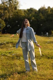Photo of Feeling freedom. Happy young woman having fun among soap bubbles in nature