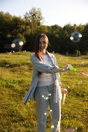 Photo of Feeling freedom. Happy young woman having fun among soap bubbles in nature