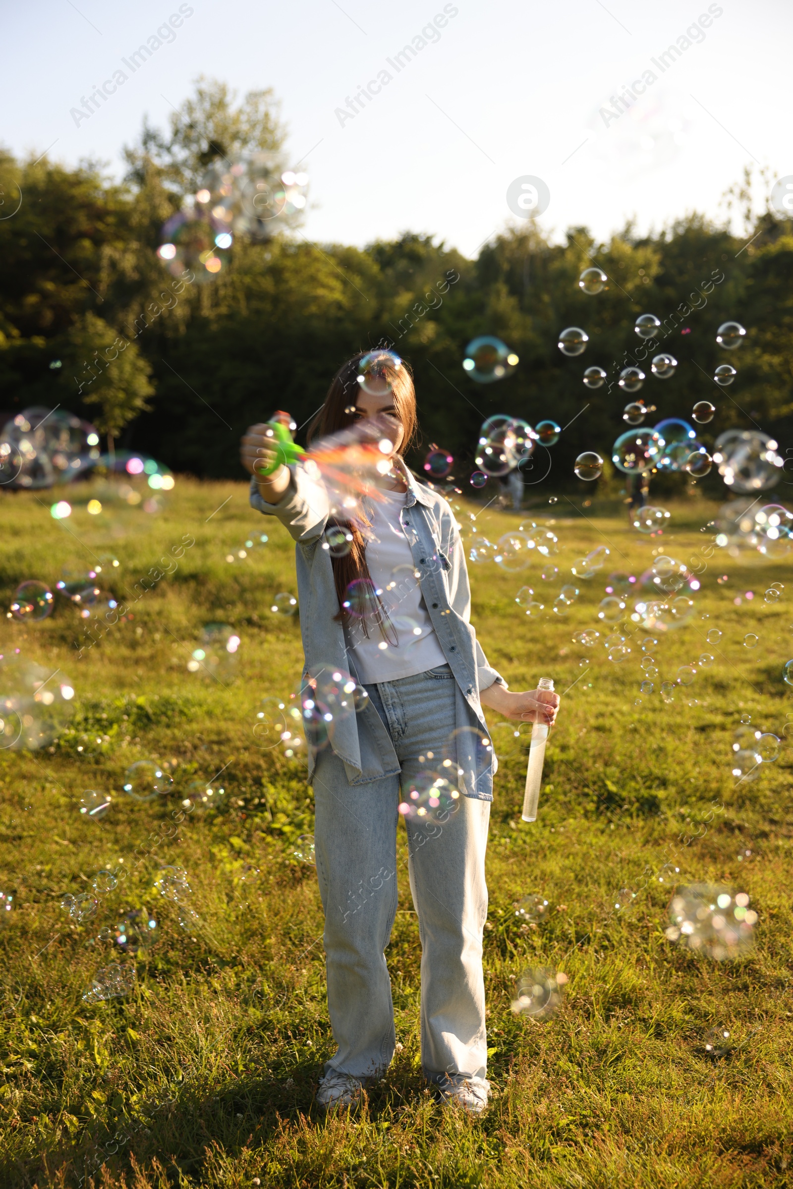 Photo of Feeling freedom. Happy young woman having fun among soap bubbles in nature