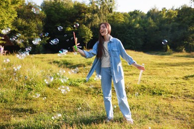 Photo of Feeling freedom. Happy young woman having fun among soap bubbles in nature