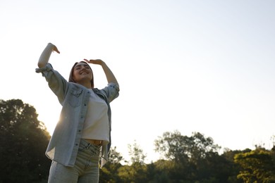 Photo of Feeling freedom. Happy young woman enjoying time in nature on sunny day, low angle view. Space for text