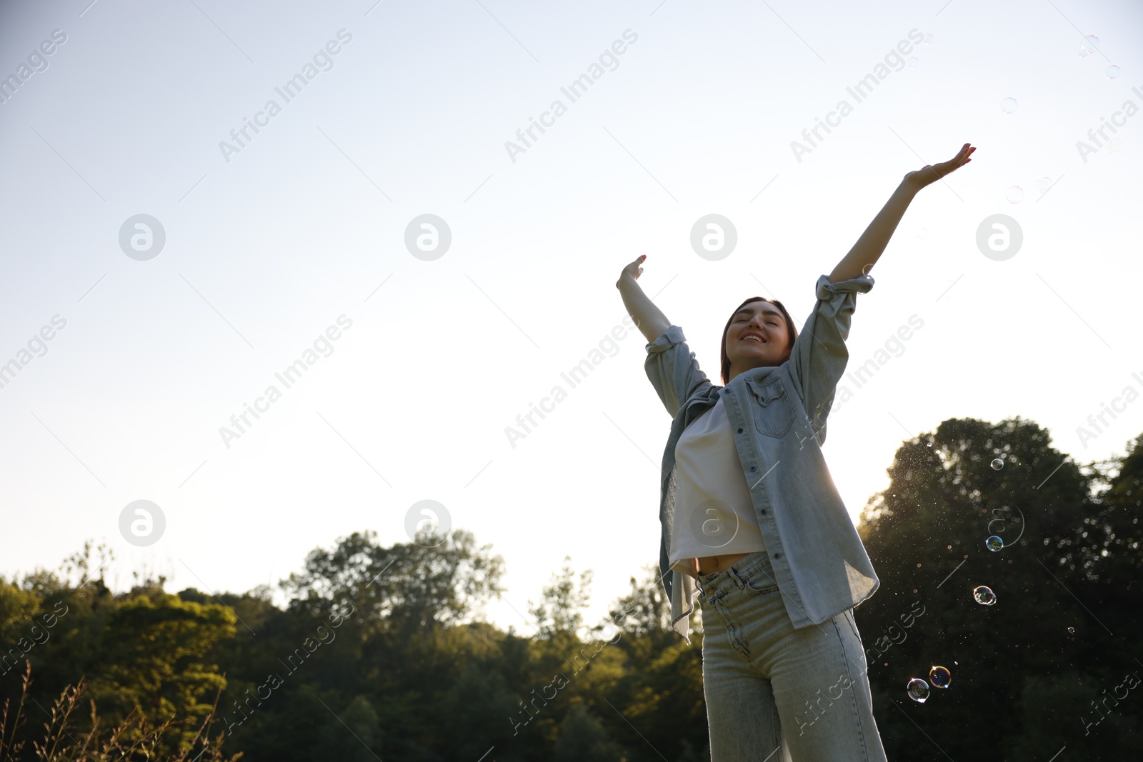 Photo of Feeling freedom. Happy young woman enjoying time in nature on sunny day, low angle view. Space for text