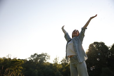Photo of Feeling freedom. Happy young woman enjoying time in nature on sunny day, low angle view. Space for text