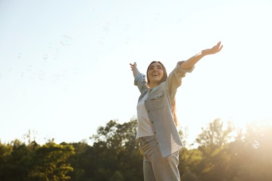 Photo of Feeling freedom. Happy young woman enjoying time in nature on sunny day, low angle view. Space for text