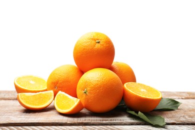 Photo of Pile of juicy oranges and green leaves on wooden table against white background