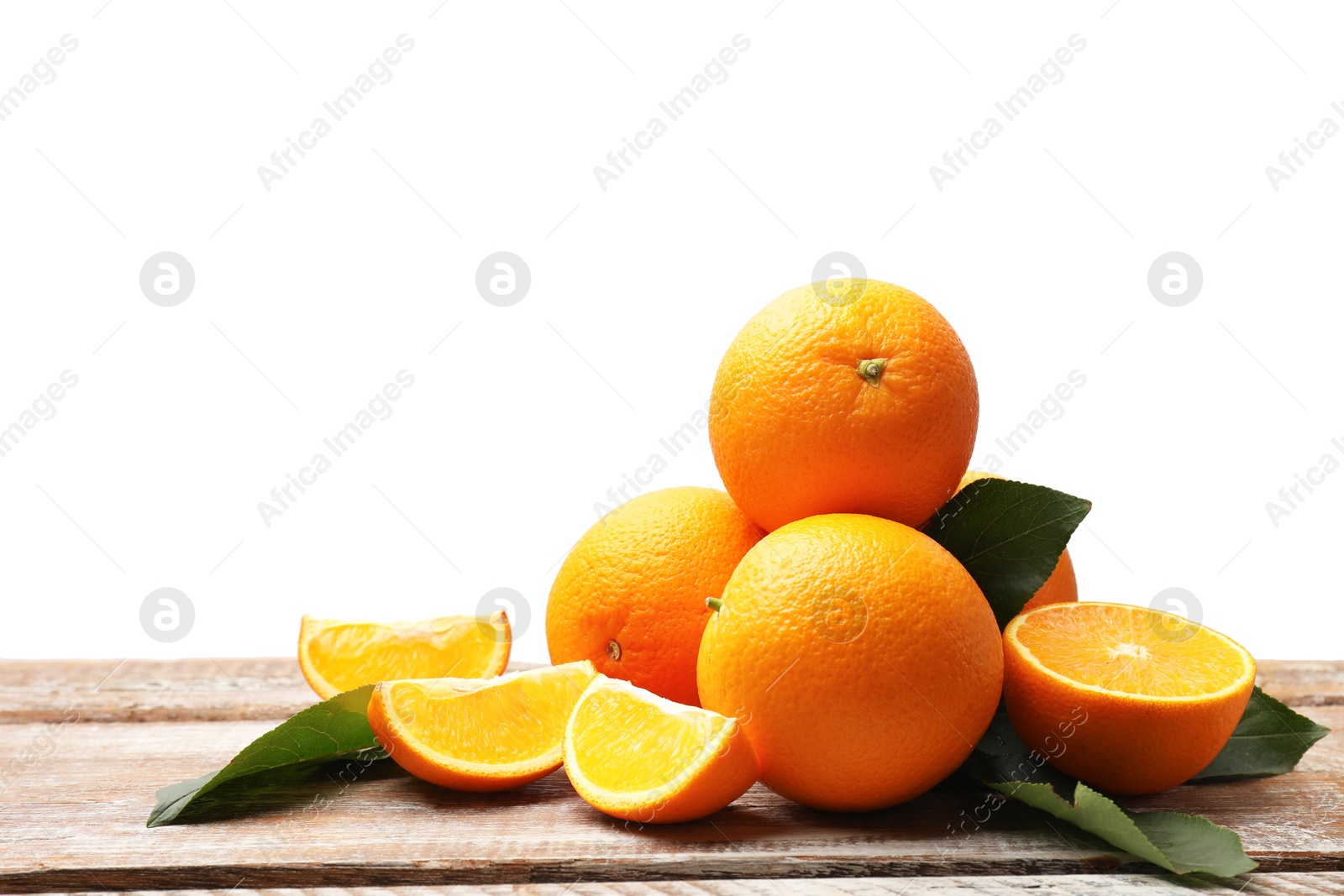 Pile of juicy oranges and green leaves on wooden table against white background Photo of Pile of juicy oranges and green leaves on wooden table against white background