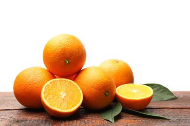 Photo of Pile of juicy oranges and green leaves on wooden table against white background