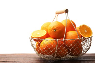 Photo of Juicy oranges in metal basket on wooden table against white background. Space for text