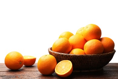 Photo of Juicy oranges and wicker basket on wooden table against white background