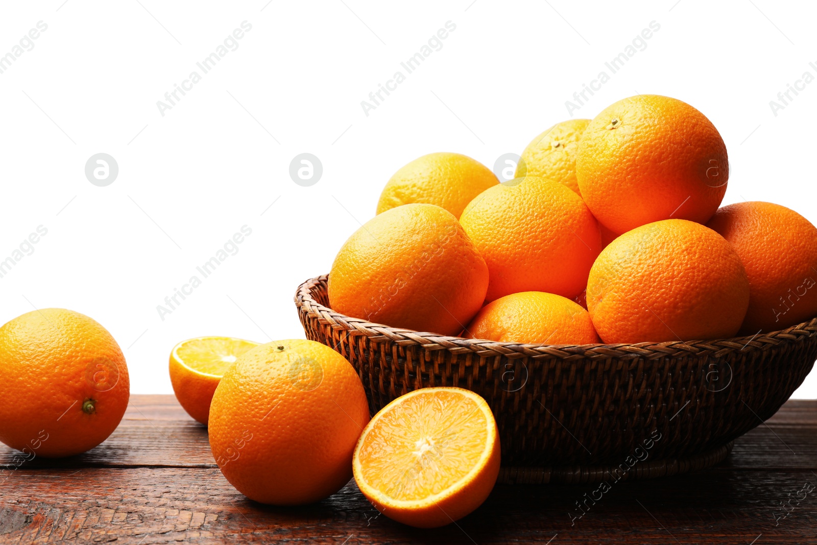 Photo of Juicy oranges and wicker basket on wooden table against white background
