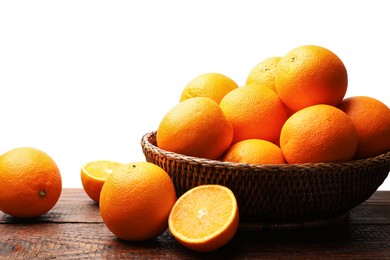 Photo of Juicy oranges and wicker basket on wooden table against white background