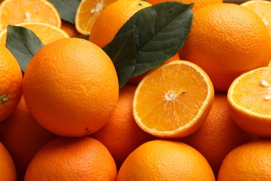 Photo of Juicy oranges and green leaves as background, closeup