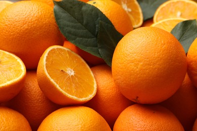 Photo of Juicy oranges and green leaves as background, closeup