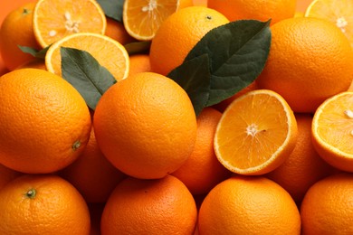 Photo of Juicy oranges and green leaves as background, closeup