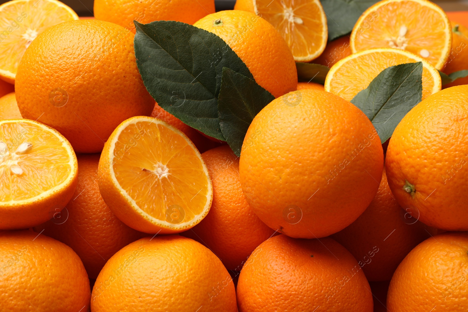 Photo of Juicy oranges and green leaves as background, closeup