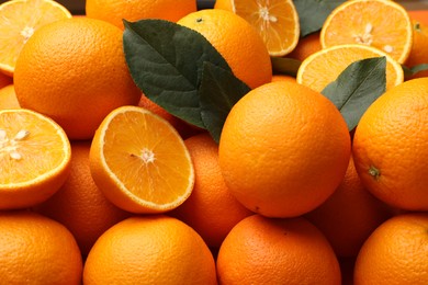 Photo of Juicy oranges and green leaves as background, closeup