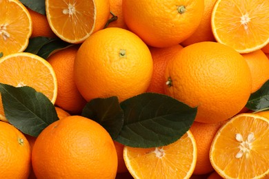 Photo of Juicy oranges and green leaves as background, top view