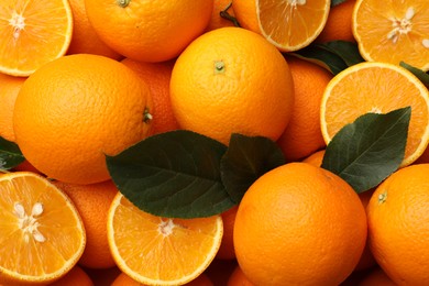Photo of Juicy oranges and green leaves as background, top view