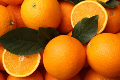 Photo of Juicy oranges and green leaves as background, top view