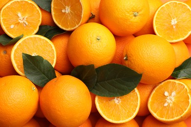 Photo of Juicy oranges and green leaves as background, top view