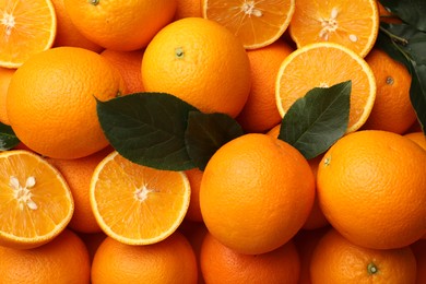 Photo of Juicy oranges and green leaves as background, top view
