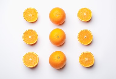 Photo of Fresh whole and cut oranges on white background, flat lay