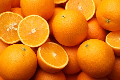 Photo of Fresh cut and whole oranges as background, top view