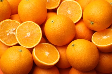 Photo of Fresh cut and whole oranges as background, top view